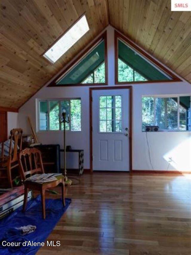 interior space with wood-type flooring, wood ceiling, and vaulted ceiling with skylight