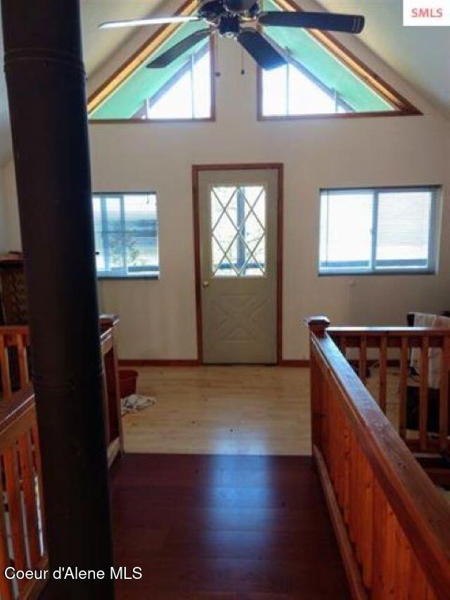 interior space with ceiling fan, high vaulted ceiling, and dark wood-type flooring