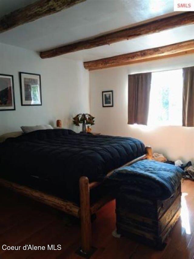 bedroom with beamed ceiling and dark hardwood / wood-style floors