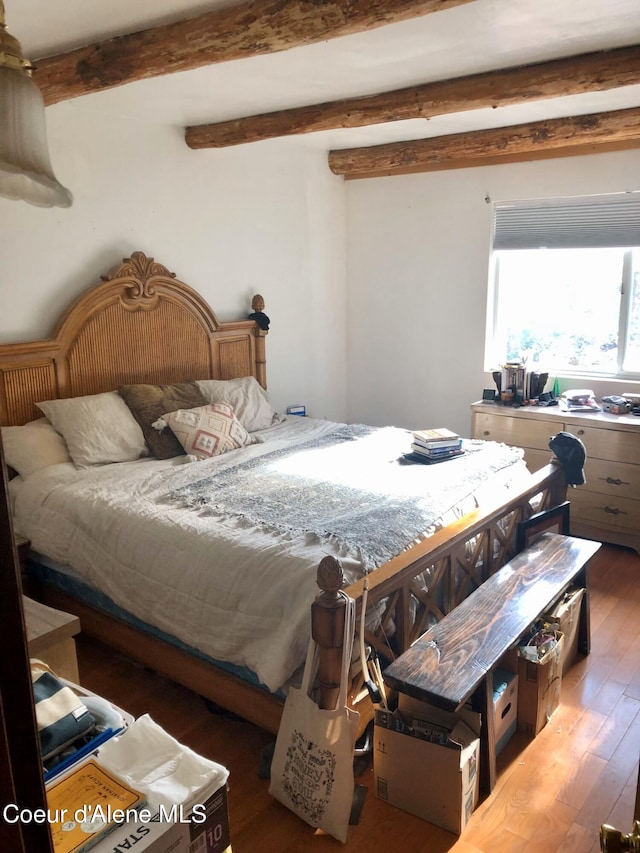 bedroom with beamed ceiling and dark wood-type flooring