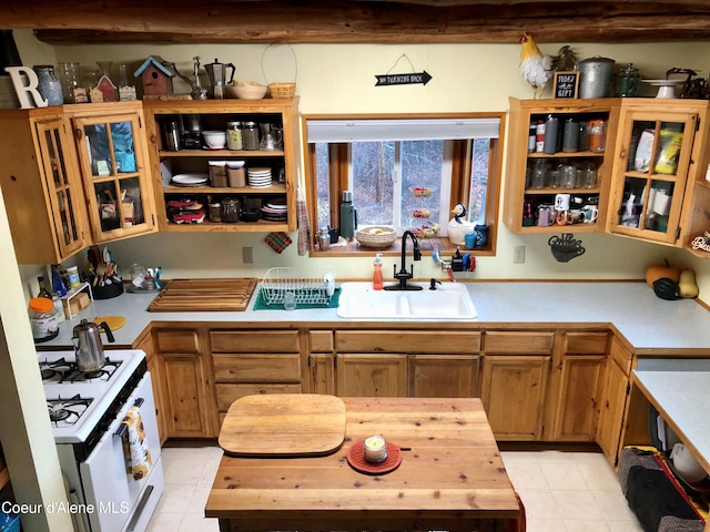 1452 Grizzly Gap Rd, Naples, ID 83847 - kitchen featuring white range with gas stovetop, a sink, light tile patterned flooring, and glass insert cabinets