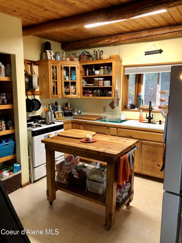 1452 Grizzly Gap Rd, Naples, ID 83847 - kitchen with white range with gas stovetop, freestanding refrigerator, wooden ceiling, beamed ceiling, and a sink