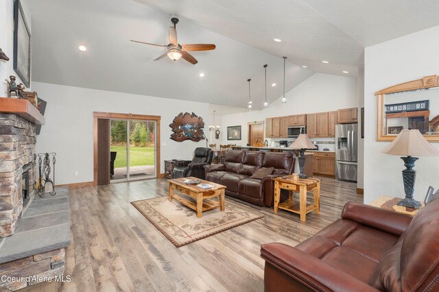 living room with ceiling fan, a fireplace, light hardwood / wood-style flooring, and high vaulted ceiling