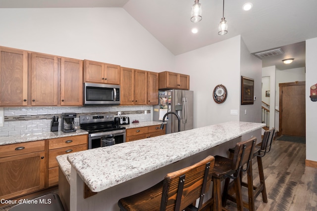 kitchen with a kitchen bar, decorative light fixtures, stainless steel appliances, tasteful backsplash, and high vaulted ceiling