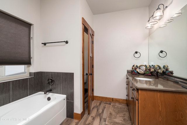 bathroom with hardwood / wood-style flooring, vanity, and a bathing tub