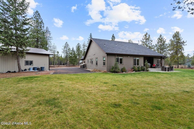 back of house with a lawn and a patio