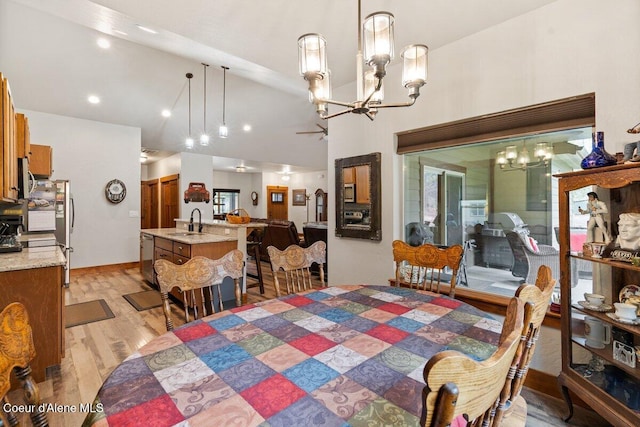 dining room with high vaulted ceiling, sink, a notable chandelier, and light wood-type flooring