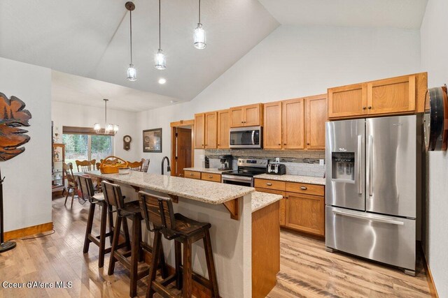 kitchen featuring a kitchen island, decorative light fixtures, stainless steel appliances, decorative backsplash, and high vaulted ceiling