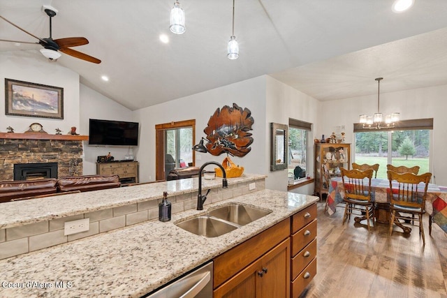 kitchen with hanging light fixtures, a wealth of natural light, light stone countertops, and sink