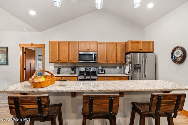 kitchen with tasteful backsplash, appliances with stainless steel finishes, and a center island with sink