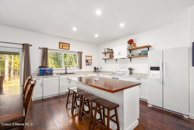 kitchen featuring dark hardwood / wood-style flooring, a breakfast bar, white cabinetry, a center island, and white appliances