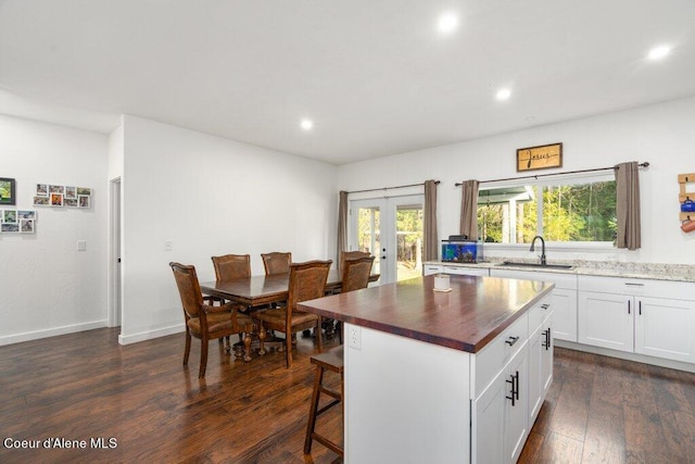 kitchen featuring sink, butcher block counters, a center island, white cabinets, and dark hardwood / wood-style floors