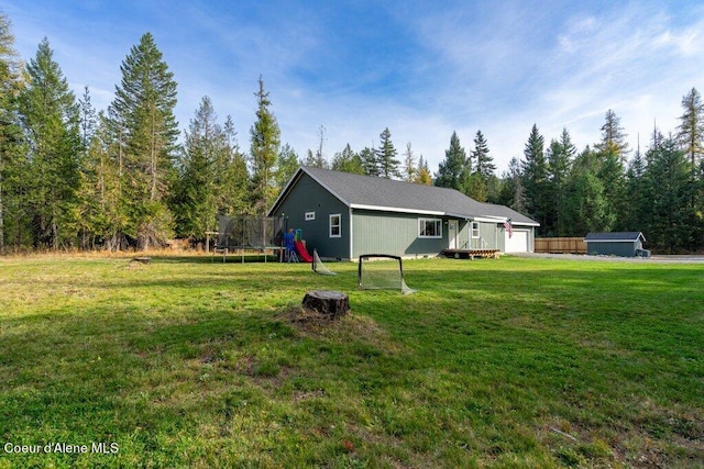 view of yard with a wooden deck, a playground, a trampoline, and a garage