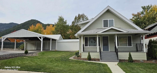 bungalow with a carport, a porch, a mountain view, and a front lawn