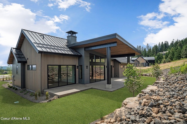 15374 S Chalone Dr, Coeur Dalene, ID 83814 - back of house featuring a standing seam roof, a chimney, a patio area, a metal roof, and a yard