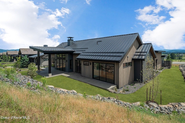 15374 S Chalone Dr, Coeur Dalene, ID 83814 - back of property featuring a standing seam roof, a chimney, a metal roof, a patio area, and a yard