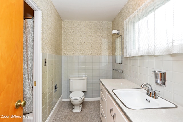 bathroom with tile walls, walk in shower, vanity, and toilet