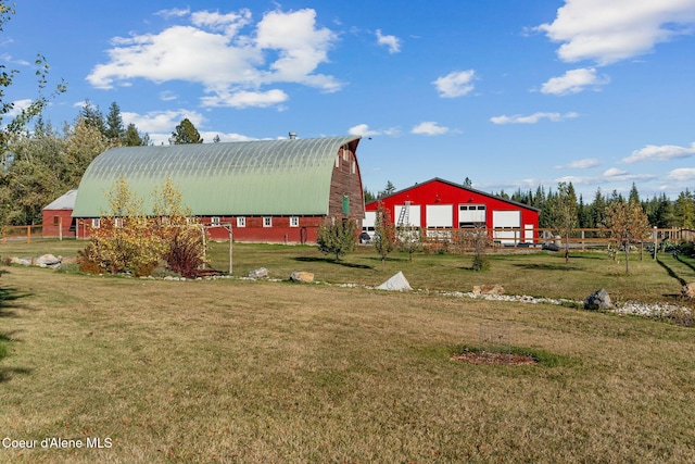 view of yard featuring a barn, an outdoor structure, fence, and a detached garage