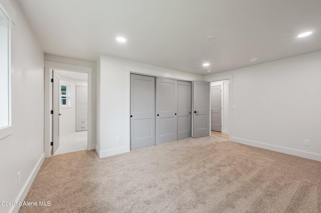 unfurnished bedroom featuring a closet and light colored carpet