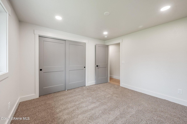 unfurnished bedroom with light carpet and a closet