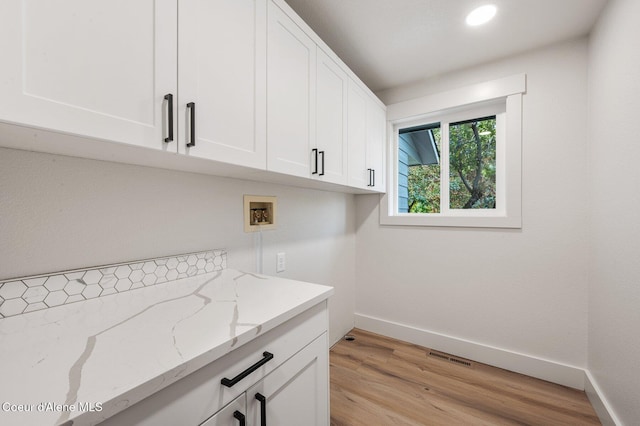 laundry room with hookup for a washing machine, cabinets, and light hardwood / wood-style flooring