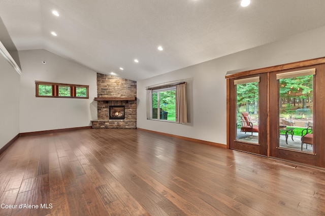 unfurnished living room with a stone fireplace, hardwood / wood-style flooring, and lofted ceiling