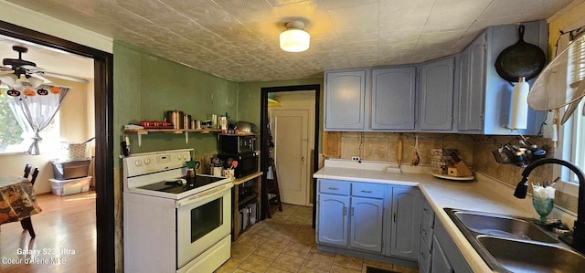 kitchen with white electric range oven, decorative backsplash, sink, and gray cabinetry