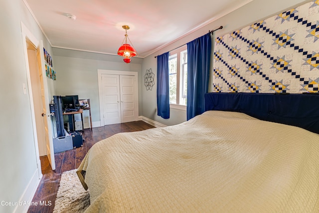 bedroom with a closet, dark hardwood / wood-style floors, and ornamental molding