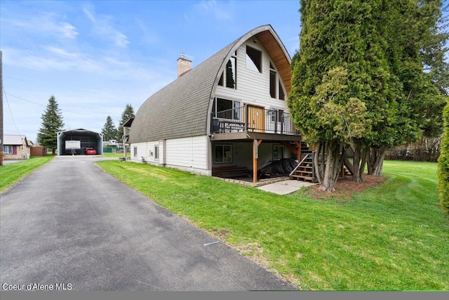 back of property featuring a wooden deck, a yard, and a carport