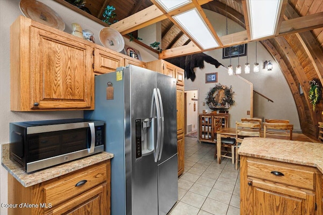 kitchen with vaulted ceiling with beams, stainless steel appliances, and light tile patterned floors