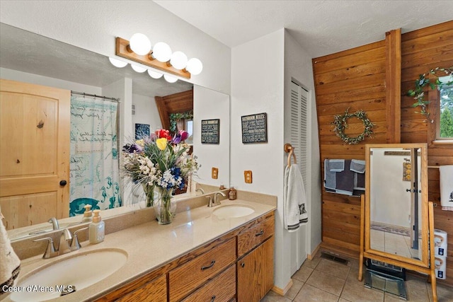 bathroom featuring vanity, tile patterned floors, a textured ceiling, and wooden walls