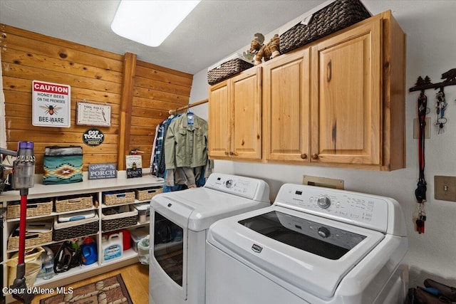 laundry area featuring light hardwood / wood-style floors, a textured ceiling, washing machine and dryer, and cabinets