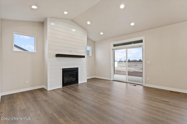 unfurnished living room with wood-type flooring, a large fireplace, and vaulted ceiling