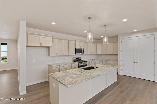 kitchen featuring dark hardwood / wood-style flooring, sink, an island with sink, and appliances with stainless steel finishes