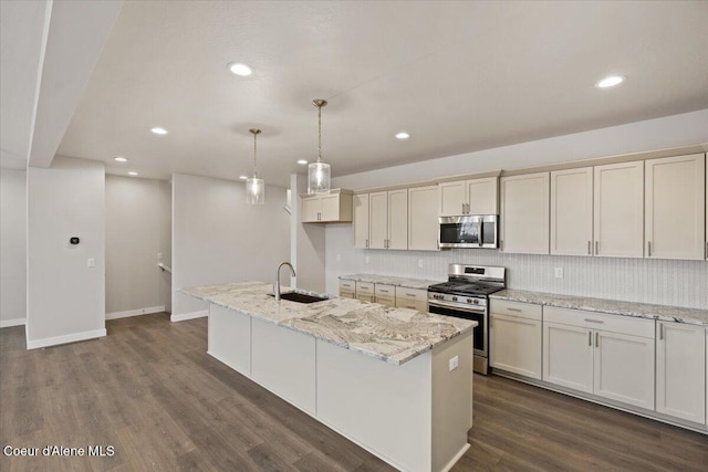 kitchen with light stone counters, an island with sink, and appliances with stainless steel finishes