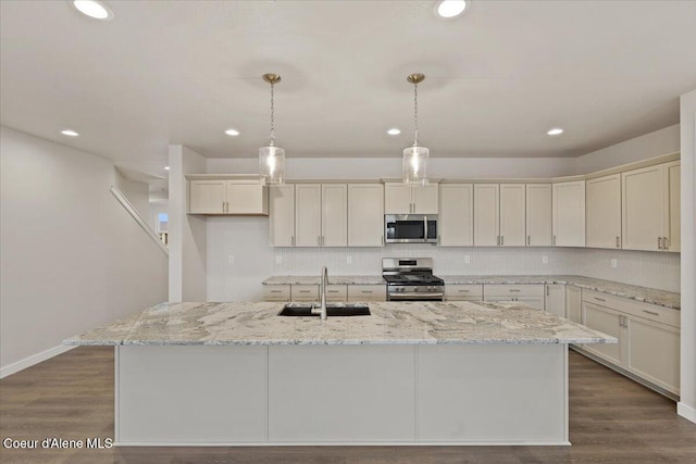 kitchen featuring sink, stainless steel appliances, dark hardwood / wood-style flooring, decorative light fixtures, and a kitchen island with sink