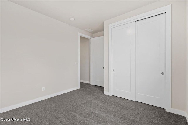 unfurnished bedroom featuring a closet and dark colored carpet