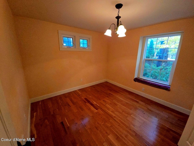 unfurnished room featuring wood-type flooring and an inviting chandelier