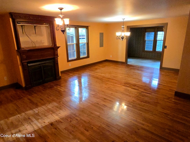 unfurnished living room with an inviting chandelier and dark hardwood / wood-style floors