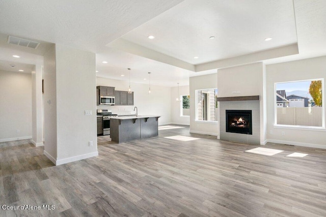 unfurnished living room with sink, hardwood / wood-style floors, and a tray ceiling