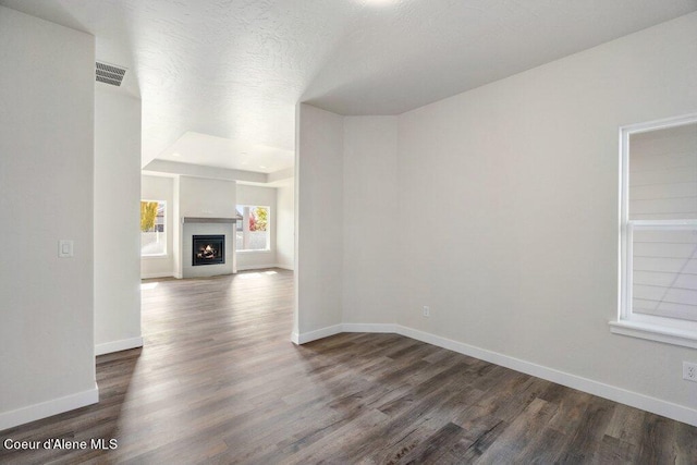 unfurnished living room featuring a textured ceiling and dark hardwood / wood-style flooring