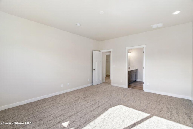 unfurnished bedroom featuring ensuite bath and carpet