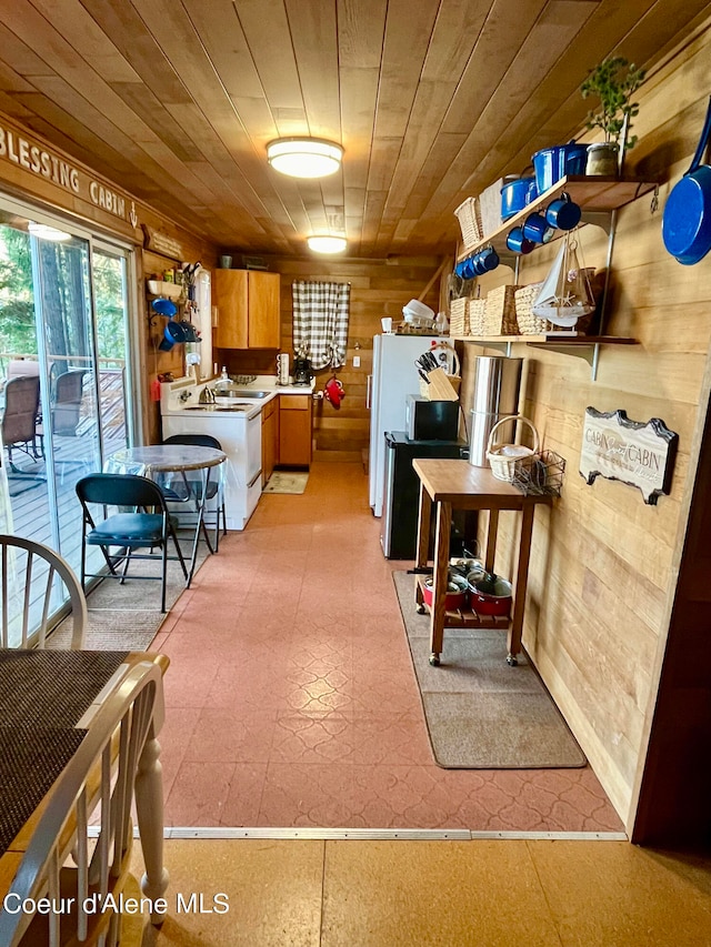 kitchen with wooden ceiling, sink, and wooden walls