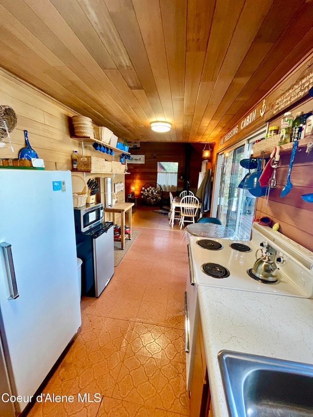 kitchen with appliances with stainless steel finishes, wood ceiling, light tile patterned flooring, and wood walls