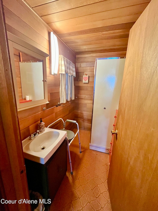 bathroom featuring vanity, wood walls, wooden ceiling, and tile patterned flooring