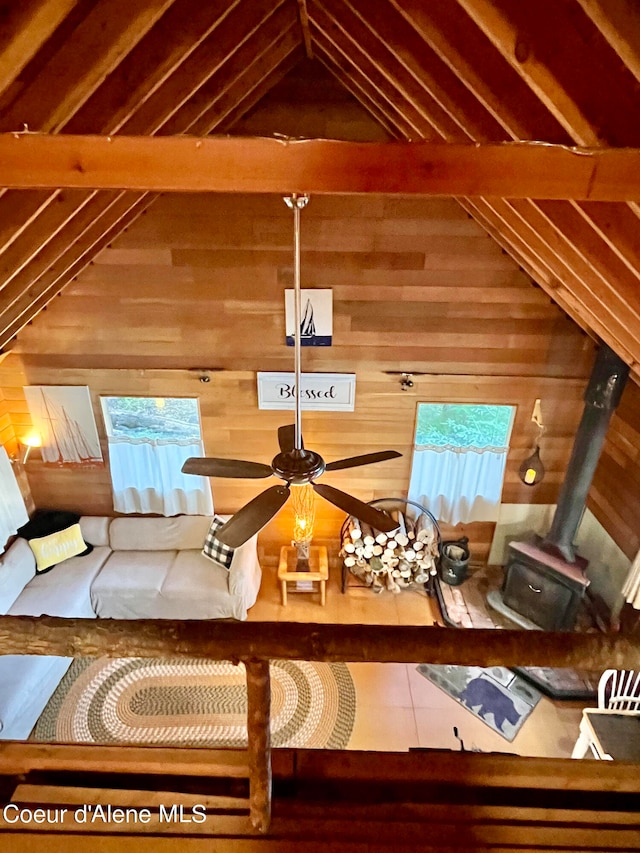 interior space featuring beam ceiling, ceiling fan, and wood walls