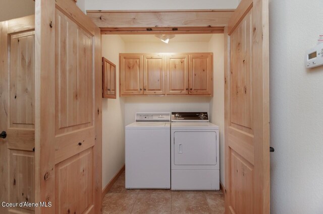 clothes washing area with independent washer and dryer, light tile patterned floors, and cabinets