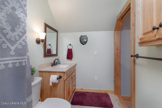 bathroom featuring vanity, toilet, and vaulted ceiling