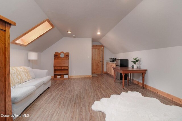 office area featuring vaulted ceiling with skylight and light hardwood / wood-style flooring