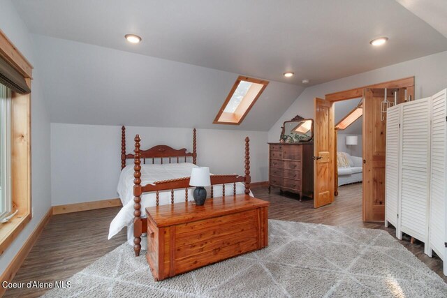 bedroom with vaulted ceiling with skylight and wood-type flooring